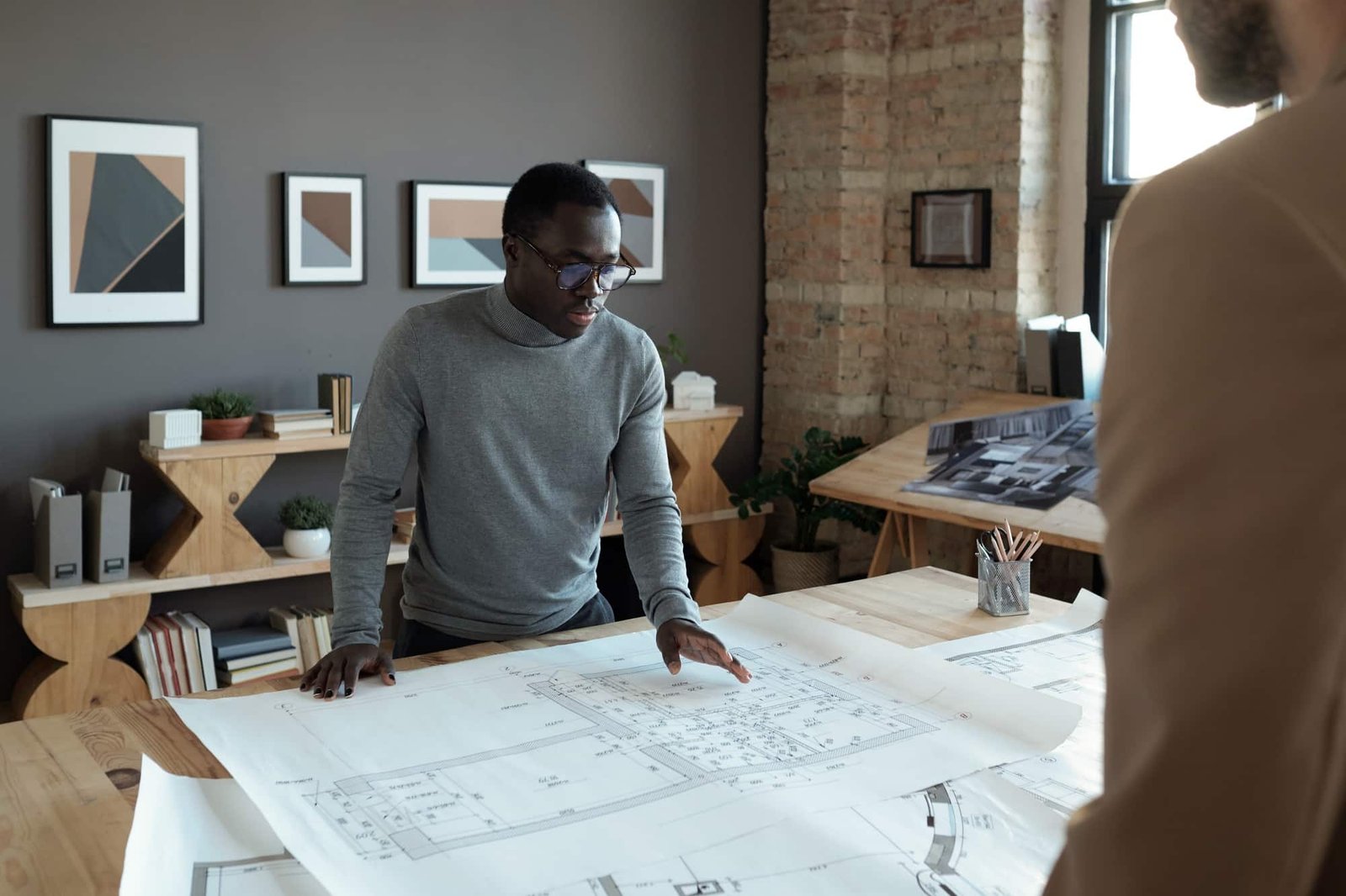 Young confident African engineer looking at sketch during discussion