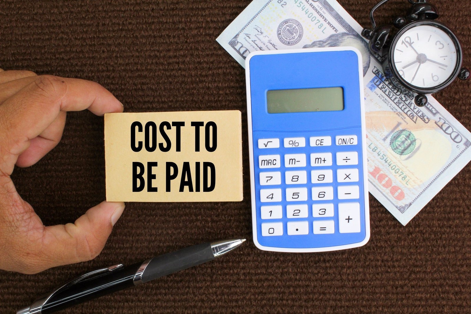 calculator, pen and paper money with the word cost to be paid.